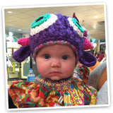 Cute baby wearing a playful purple knitted monster hat with crocheted eyes, ears, and horns, adding a touch of whimsy to their adorable ensemble.