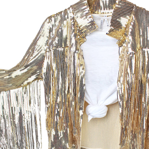Close-up of gold sequin fringe jacket with popped collar on a wooden hanger against a white background. Elegant details for a glamorous wardrobe addition.
