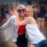 Stylish silver sequin fringe jacket worn at a music festival, the wearer posing with a friend. Radiating glamour and festival chic for an unforgettable look.