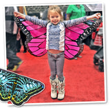 Photo of young girl spreading out butterfly wings with arms outstretched