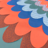 Close-up of cape layers of patterned orange, blue, green, and teal fabric