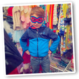Young boy confidently wearing a superhero cape and matching mask, striking a dynamic pose with boundless energy and imagination.